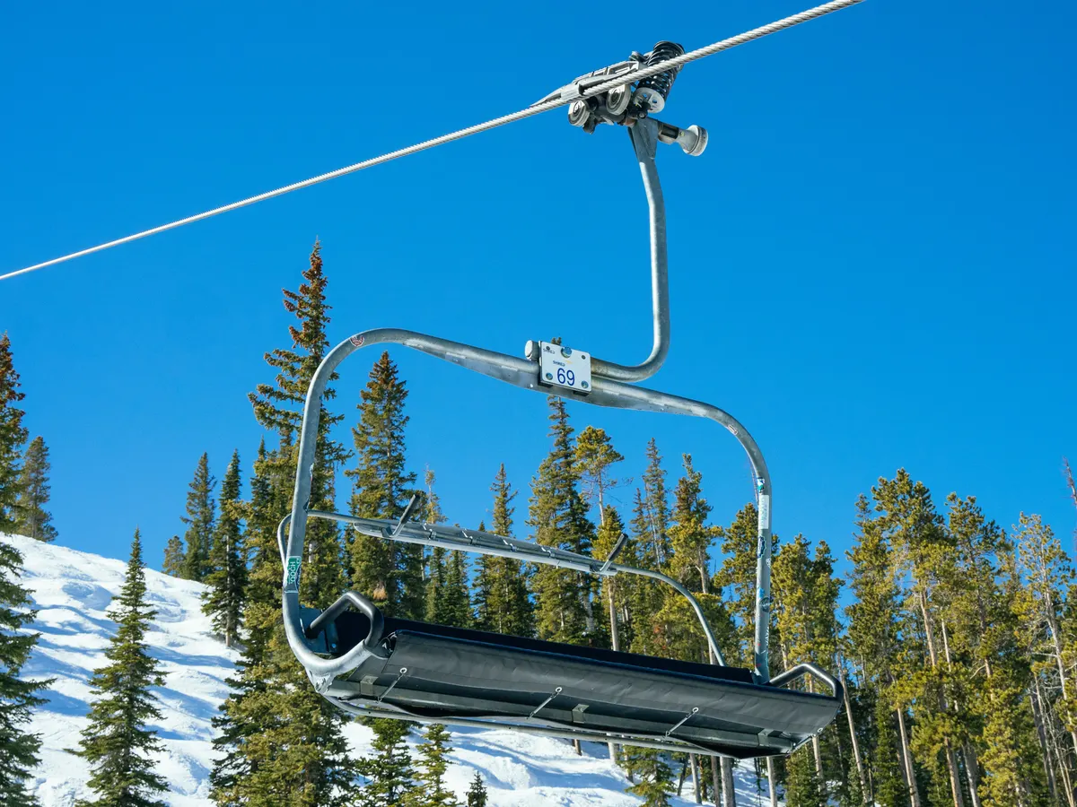 Ski chairlift over snow-covered pines under a clear blue sky